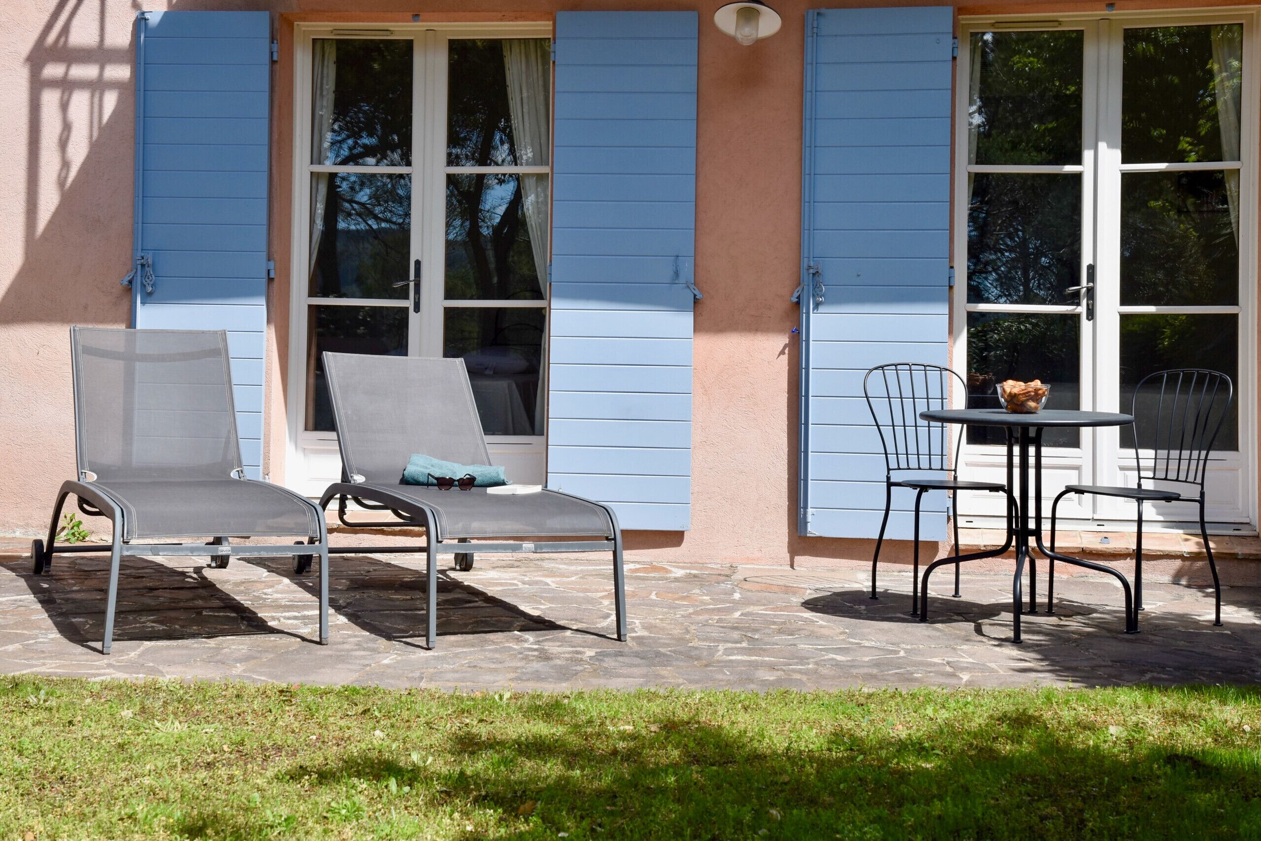 Eine Terrasse mit zwei Liegestühlen, einem Tisch mit Stühlen und einem Brotkorb.