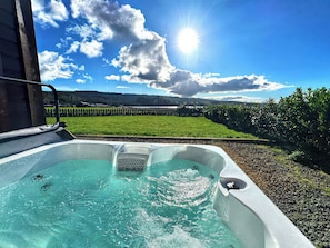 Un jacuzzi con vistas a un campo verde y montañas al fondo.