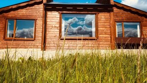 A wooden cabin with large windows, a pitched roof, and a clear sky. - No 6 (Enniskillen)