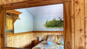A bedroom with a wooden headboard, a bed with patterned bedding, a nightstand, and a wall-mounted mirror. - No 6 (Enniskillen)