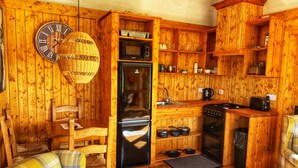 A wooden interior with a kitchen area, including a refrigerator, stove, and microwave.