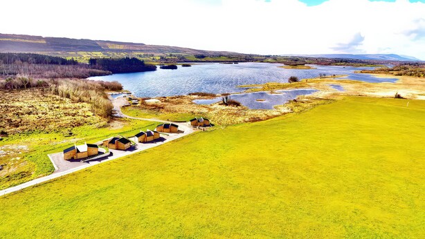 A lakeside property with wooden cabins, a grassy field, and a view of the lake.