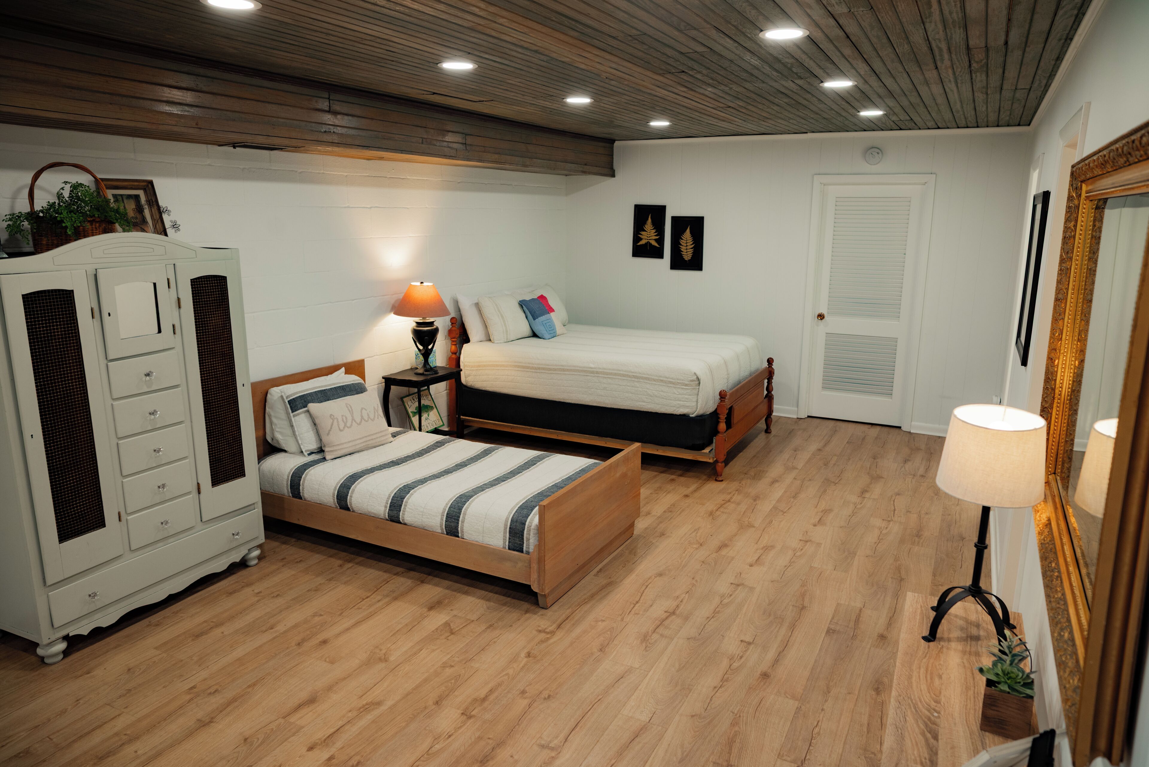 A bedroom with a bed, a nightstand, a dresser, and a mirror.