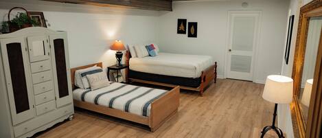 A bedroom with a bed, a nightstand, a dresser, and a mirror.