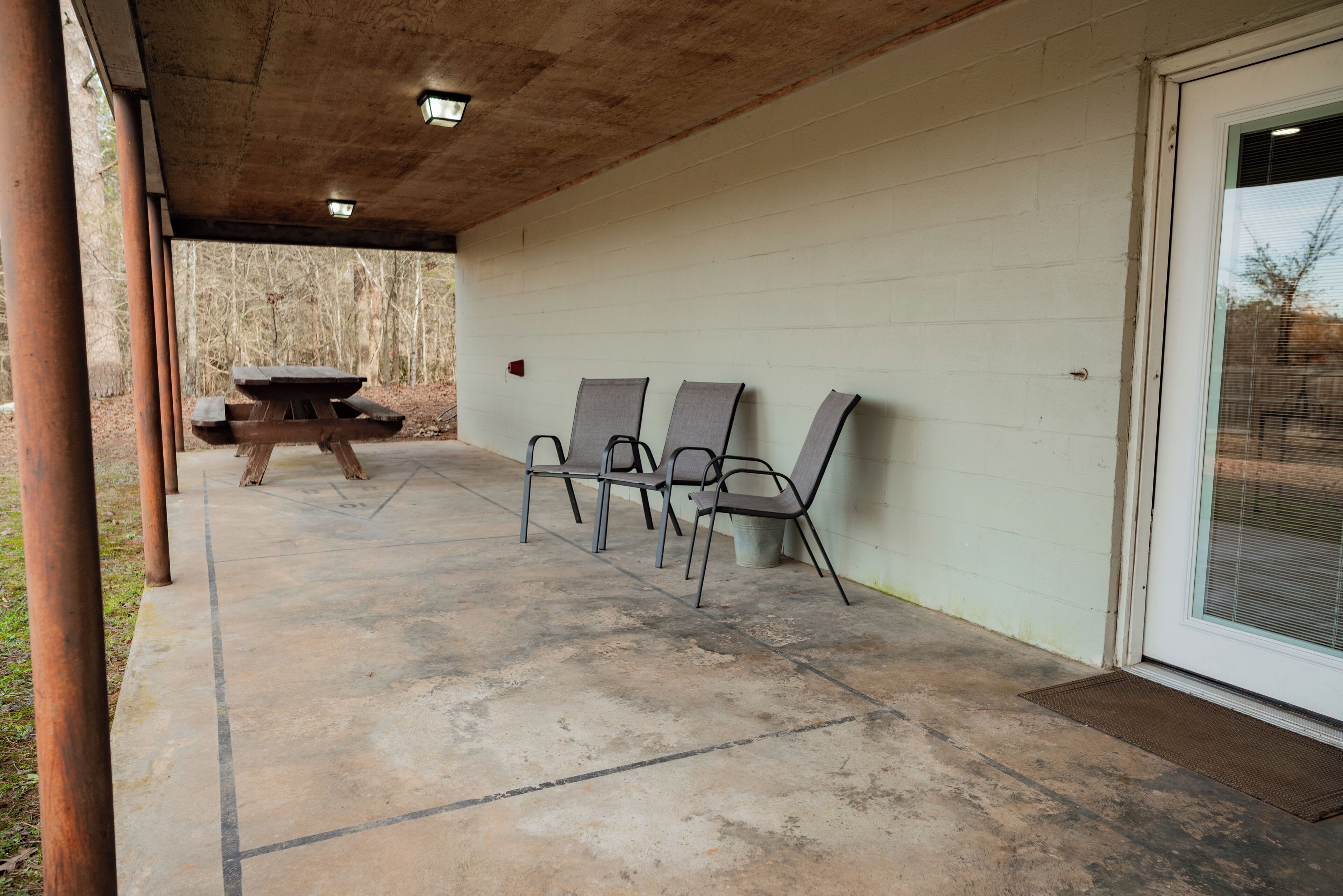 Un patio al aire libre con piso de concreto, una mesa de picnic y cuatro sillas.