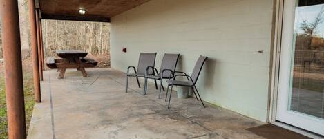 Un patio al aire libre con piso de concreto, una mesa de picnic y cuatro sillas.