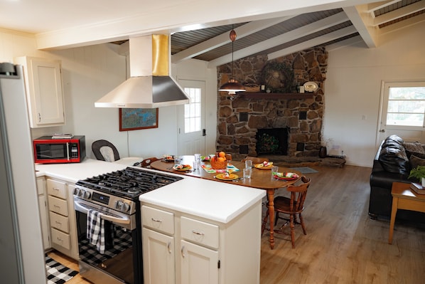 A kitchen with a stove, microwave, and dining area with a table and chairs.