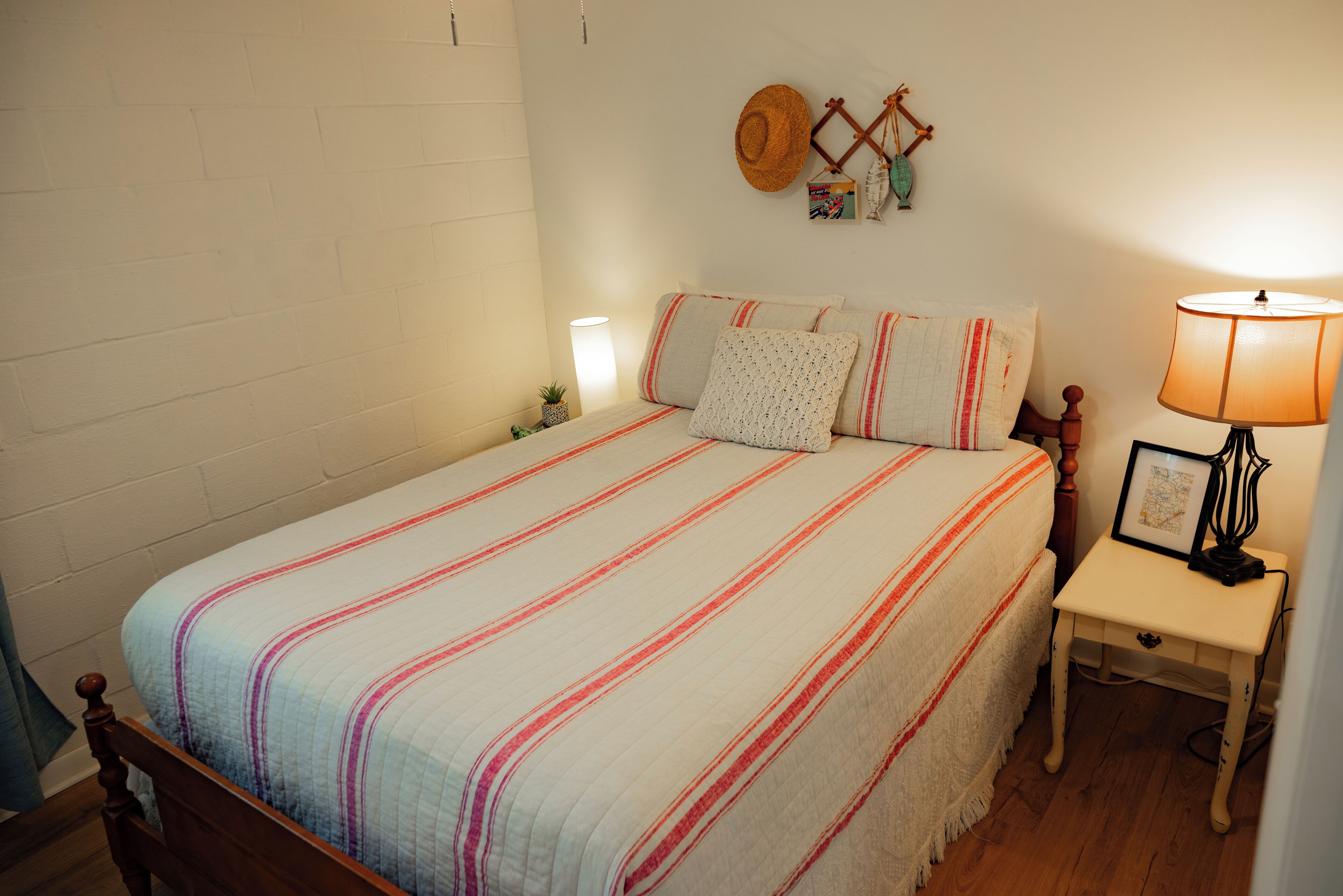 Une chambre à coucher avec un lit, une table de chevet, une lampe et des éléments de décoration murale.