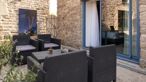 An outdoor seating area with wicker furniture and a stone wall. - Lochrist, Calzac Moulin Guest Room with Terrace, Wi-Fi, and Air Conditioning in High Season (Theix-Noyalo)
