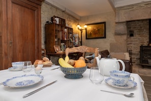 A dining table set with plates, a fruit bowl, a teapot, and a cup. - Locmariaquer Guest Room with Terrace, Wi-Fi, and Air Conditioning in High Season (Theix-Noyalo)