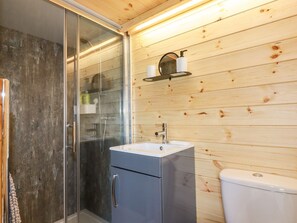 Un baño con cabina de ducha de vidrio, un lavabo con espejo y un inodoro.