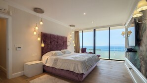 A bedroom with a large bed, bedside tables, a fluffy rug, and a view of the sea through large windows. - Villa Lux Calle Francia (Costa Adeje)
