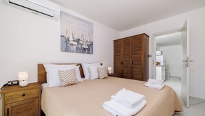 Un dormitorio con cama, armario de madera, mesita de noche y un cuadro en la pared.