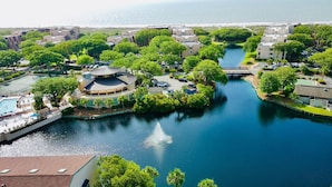 A waterfront property with a central circular building, a swimming pool, and a canal. - Island Club 106 | Pool, Hot Tub, Tennis & Beach (Hilton Head Island)