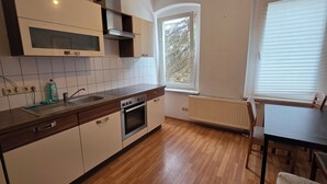 A kitchen with a window, a sink, an oven, and a dining area with chairs. - Cozy 1 bedroom apartment in a quaint Chemnitz neighborhood (Chemnitz)