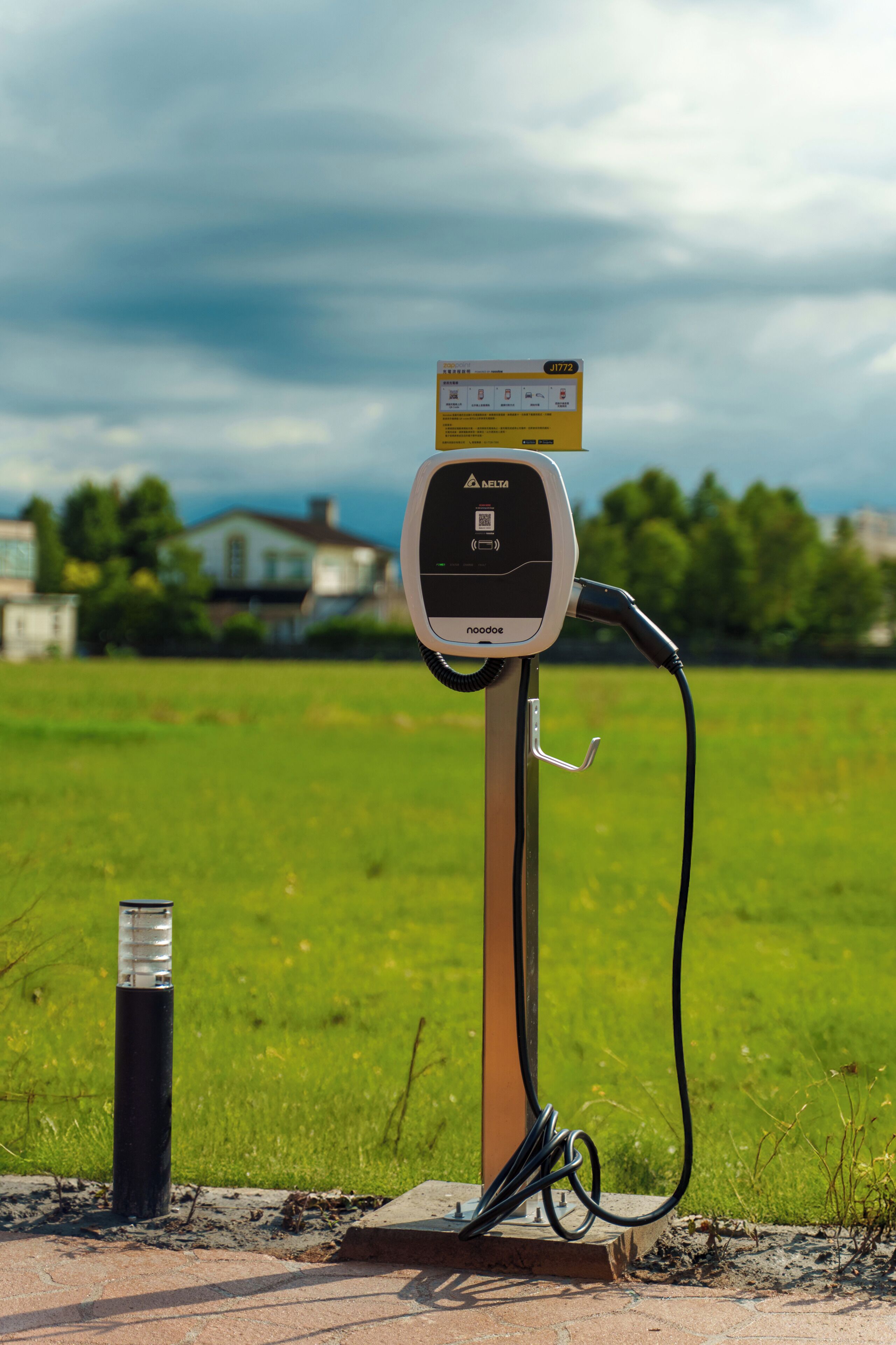 An electric vehicle charging station with a digital display, a cable, and a pole.