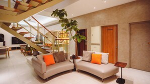 Een moderne woonkamer met een gebogen bank, een trap en een grote potplant.