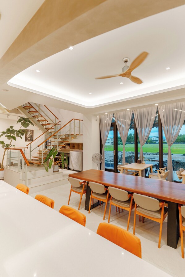 A modern dining area with a long table, chairs, and a staircase leading to an upper level. - Yosemite No.2 (Yilan)