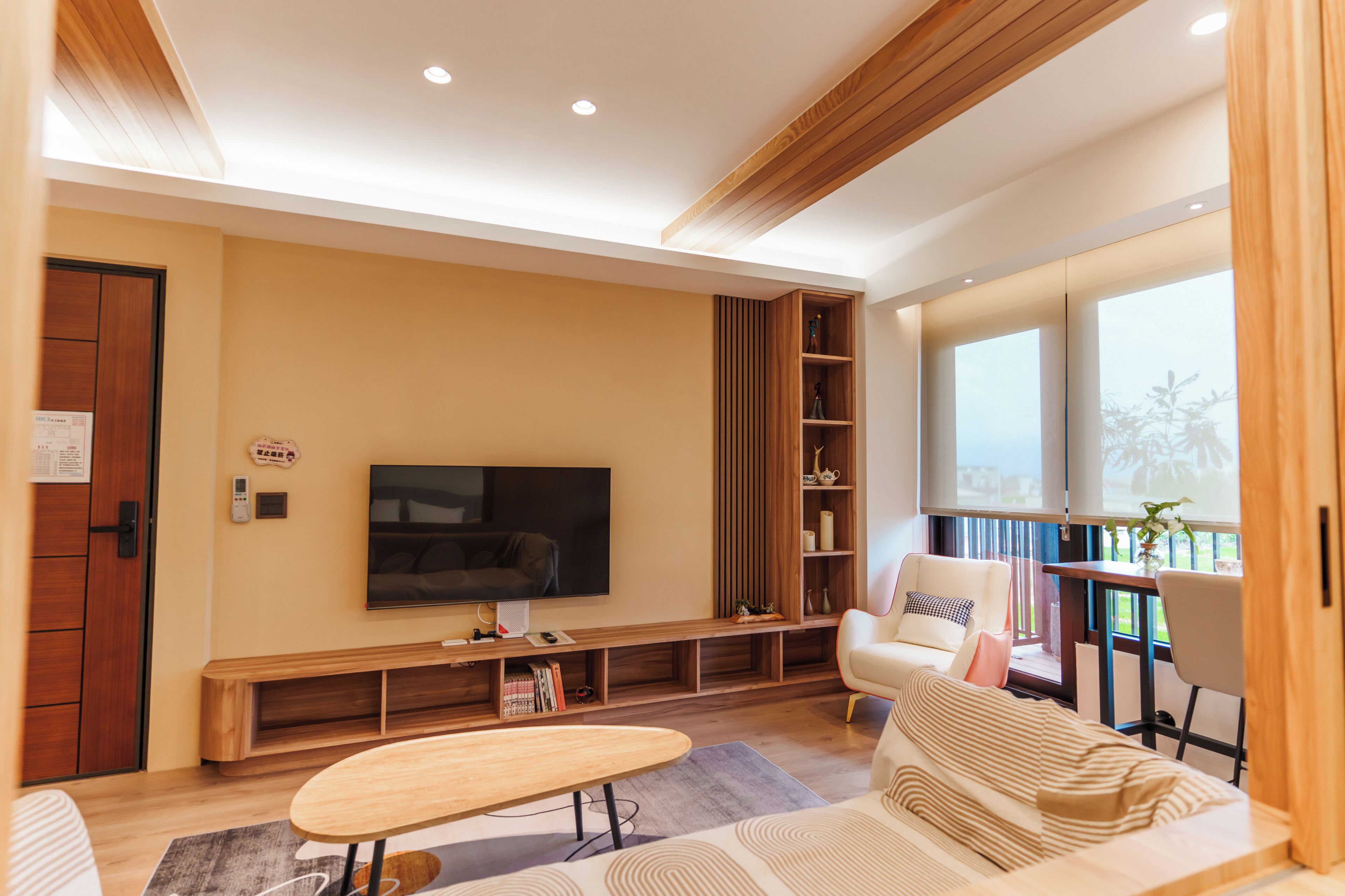 A modern living room with a flat-screen TV, a sofa, a coffee table, and a bookshelf.