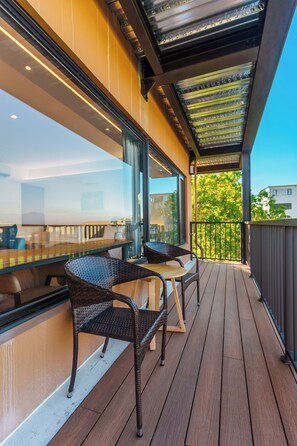 A wooden deck with outdoor seating, a glass wall, and a view of greenery. - Yosemite No.2 (Yilan)