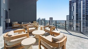 A rooftop terrace with outdoor seating, a city view, and a modern building in the background. - Modern Studio Downtown Miami Amazing Amenities (Miami)