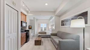 A compact living space with a kitchenette, a sofa, a bedside table, and a lamp. - Family 2-bedroom Suite in Prime Orlando Location (Orlando)