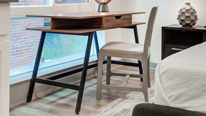 Une chambre moderne équipée d’un bureau, d’une chaise, d’une lampe et d’un objet décoratif posé sur une table de chevet.