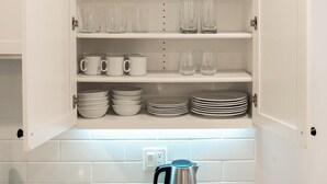 Un meuble de cuisine avec des étagères contenant des verres, des tasses et des assiettes.