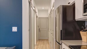 A narrow hallway with a kitchen on one side, featuring stainless steel appliances and a wooden countertop. - Prime Ludlow Studio | Steps from UPenn & CHOP (Philadelphia)