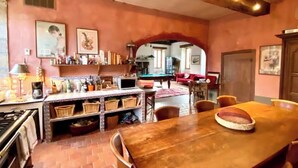 A kitchen with a dining table, a pool table, and a red sofa. - Former mill of the Château de Bourbilly transformed into a pretty country house (Vic-de-Chassenay)