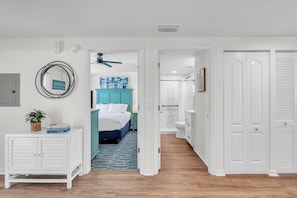A hallway leading to a bedroom with a bed, a white cabinet, and a ceiling fan. - Sunset Vistas 503n (Treasure Island)