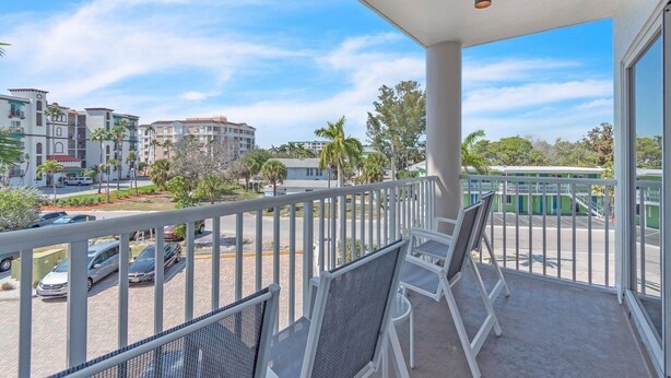 A balcony with white railings, a view of a parking lot, and buildings in the background. - Sunset Vistas 302n (Treasure Island)