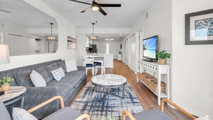 A modern living room with a sofa, coffee table, and TV. - Sunset Vistas 302n (Treasure Island)