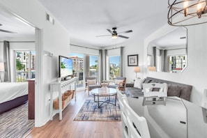 A modern hotel room with a bed, seating area, TV, and large windows. - Sunset Vistas 302n (Treasure Island)