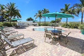A poolside area with lounge chairs, umbrellas, and a small pool. - Sunset Vistas 302n (Treasure Island)