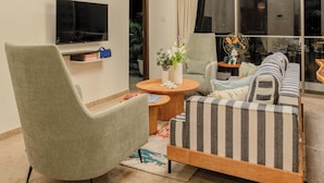 Una sala de estar con sofá, sillón, televisor y una araña.