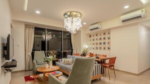 Una sala de estar moderna con un sofá, sillones, una mesa de comedor y una araña.