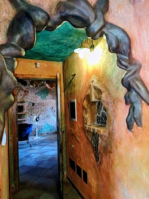 A narrow hallway with a brick wall, a fan, and a door leading to an outdoor area. - Room 'Guell' with Private Bathroom in the Hallway (Teulada)