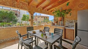 Eine Terrasse im Freien mit Tisch, Stühlen, einem Kühlschrank und Blumentöpfen.