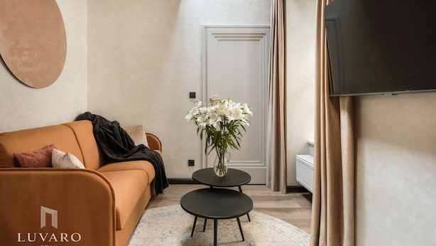 Een moderne woonkamer met een bank, een klein tafeltje met een bloemenvaas, een flatscreen-tv en een deur.