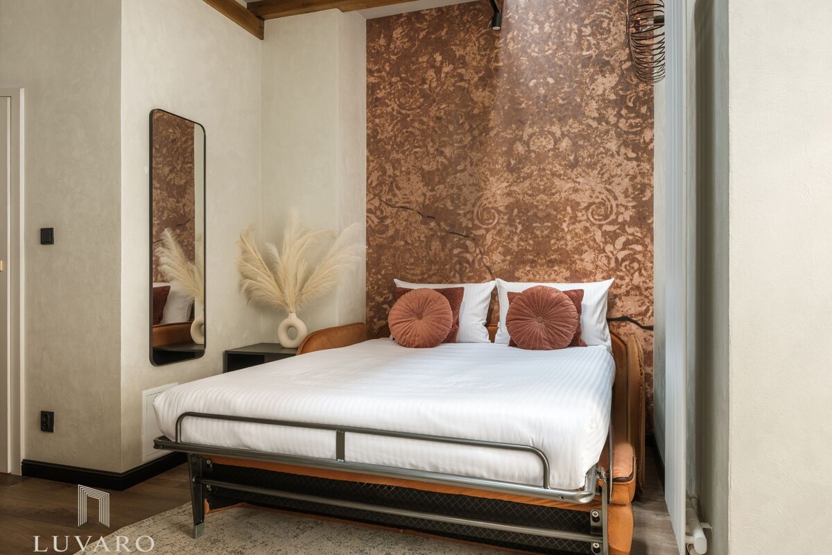 Un dormitorio con una cama, una mesita de noche, un espejo y una pared con diseño texturizado.