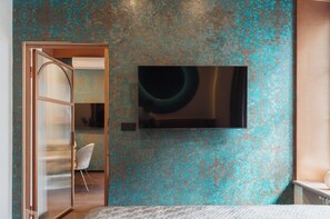 A bedroom with a bed, a TV mounted on the wall, and a door leading to another room. - Rynek 29 Aparthotel — Main Square “Cu Residence” — Kraków Old Town — by Luvaro (Kraków)