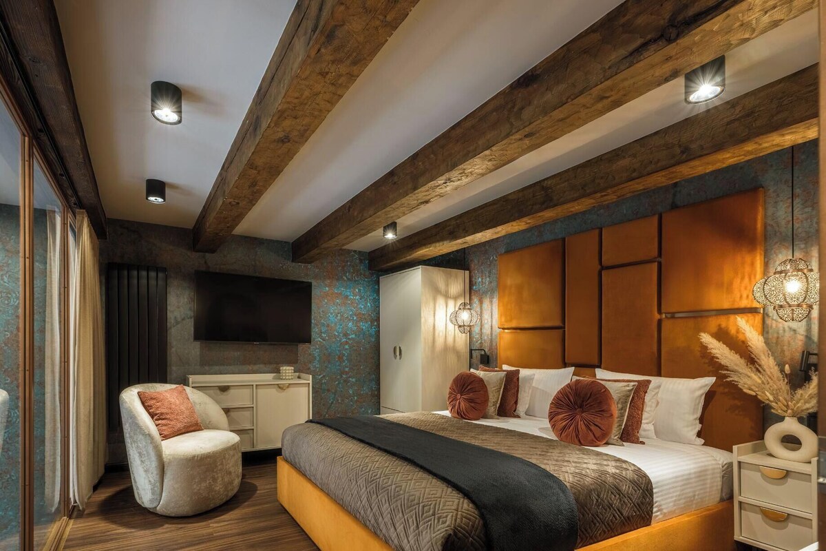 Un dormitorio con una cama grande, televisor, escritorio y silla.