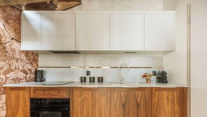 Eine moderne Küche mit Holzausstattung, einem Backofen, einer Kaffeemaschine und einem Spülbecken.