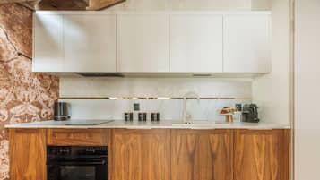 Cocina moderna con armarios de madera, horno empotrado, cafetera y un lavamanos.