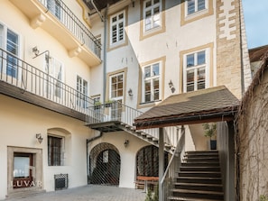 A multi-story building with a central staircase, arched doorways, and a balcony. - Rynek 29 Aparthotel — Main Square “Cu Residence” — Kraków Old Town — by Luvaro (Kraków)