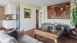 A living room with a sofa, a coffee table, a painting, and a bed. - Stylish Duplex Penthouse with Private Terraces in Ciudad Lineal (Madrid)