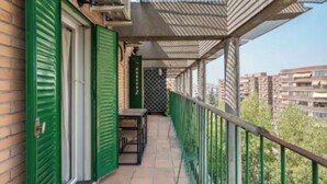A balcony with green shutters, a table, and a chair. - Stylish Duplex Penthouse with Private Terraces in Ciudad Lineal (Madrid)