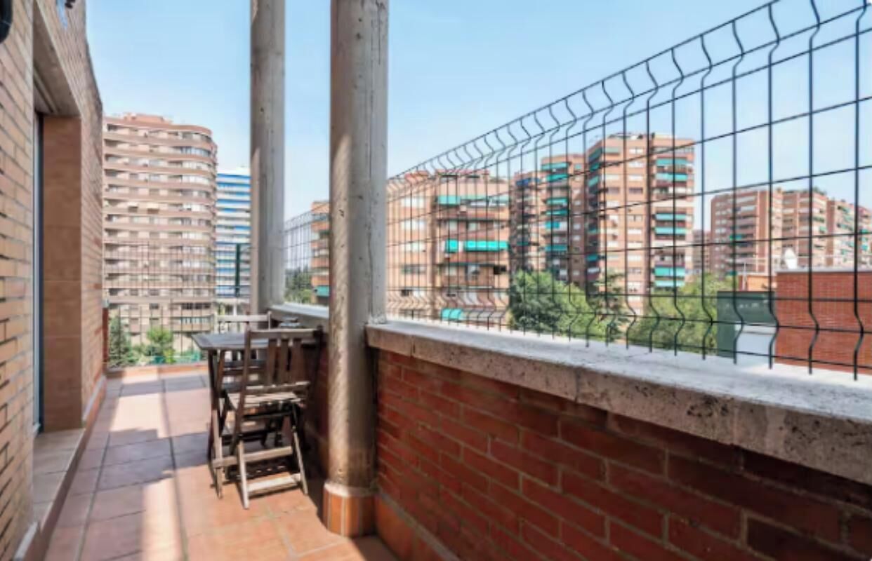 Ein Balkon mit Metallzaun, Ziegelwand und Blick auf umliegende Gebäude.