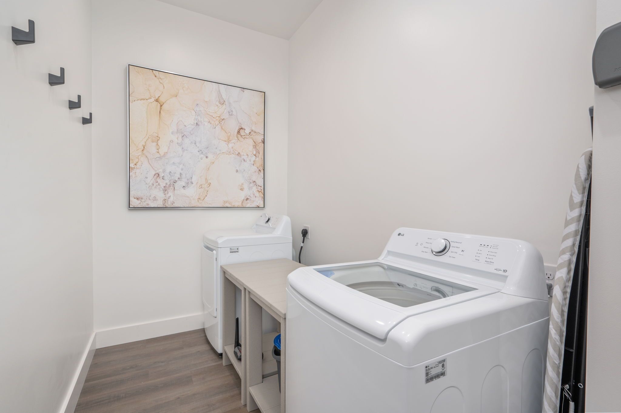 A laundry room with a washing machine, dryer, and a marble-patterned wall art piece.